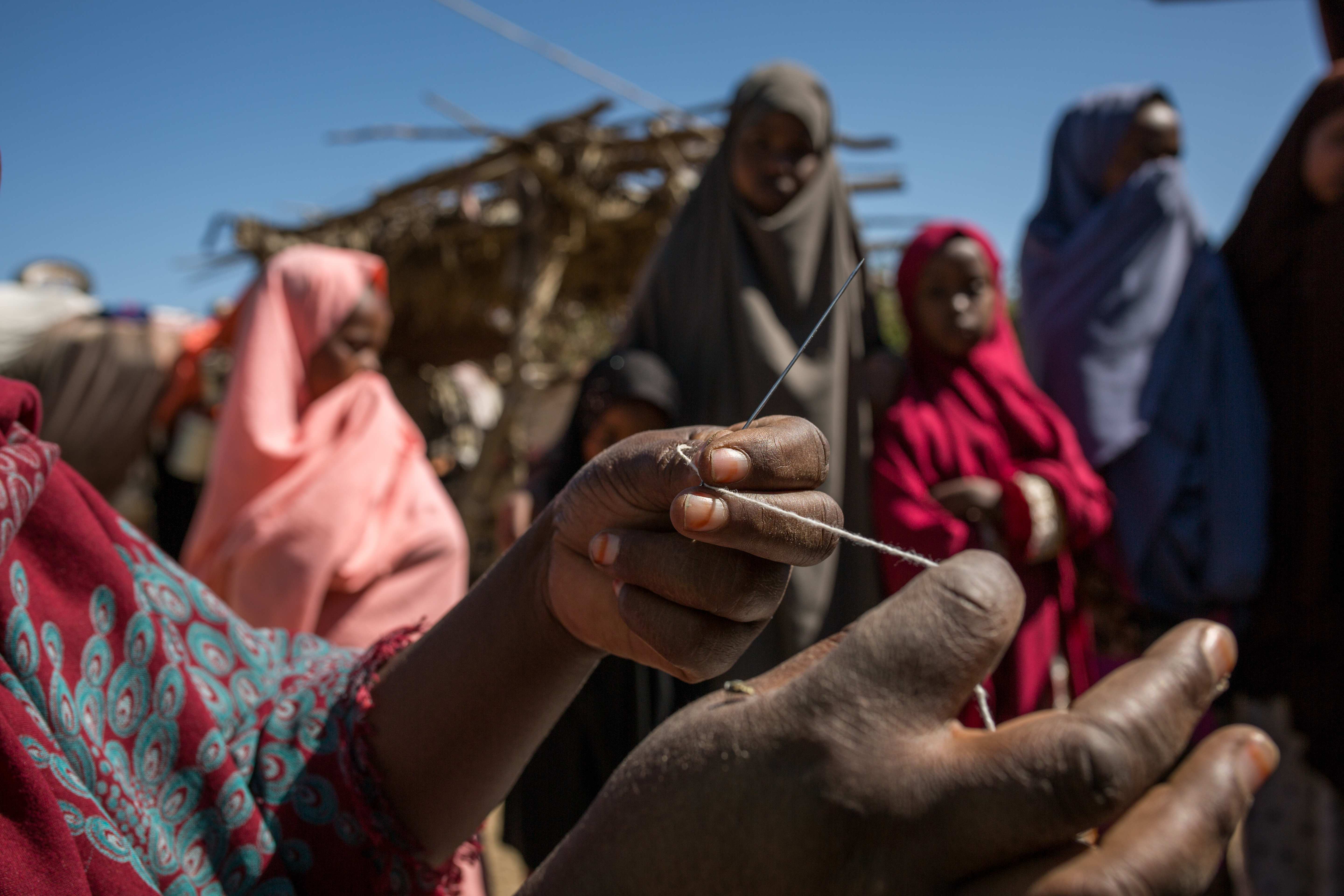 Khadra zeigt Nadel und Faden, mit denen sie die Mädchen vernäht hat (Quelle: Mustafa Saeed/Kindernothilfe)