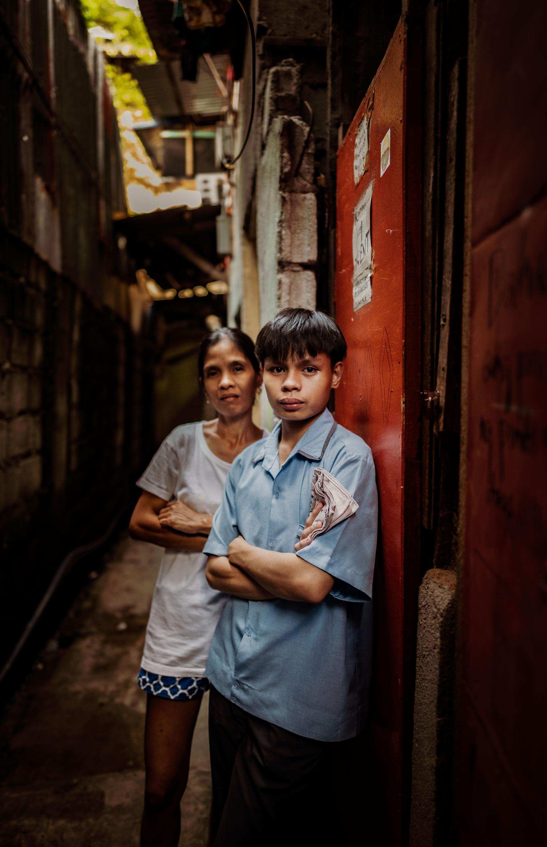 Ein Junge und seine Mutter stehen an eine Wand gelehnt in einem Slum der philippinischen Hauptstadt Manila (Quelle: Jakob Studnar)
